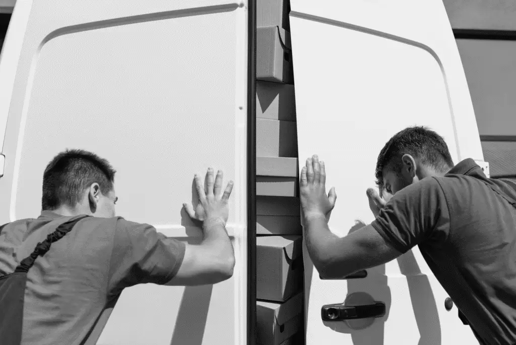 To mænd lukker flyttebil med flyttekasser, klar til afrejse.